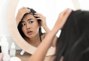 woman looking at hair in mirror